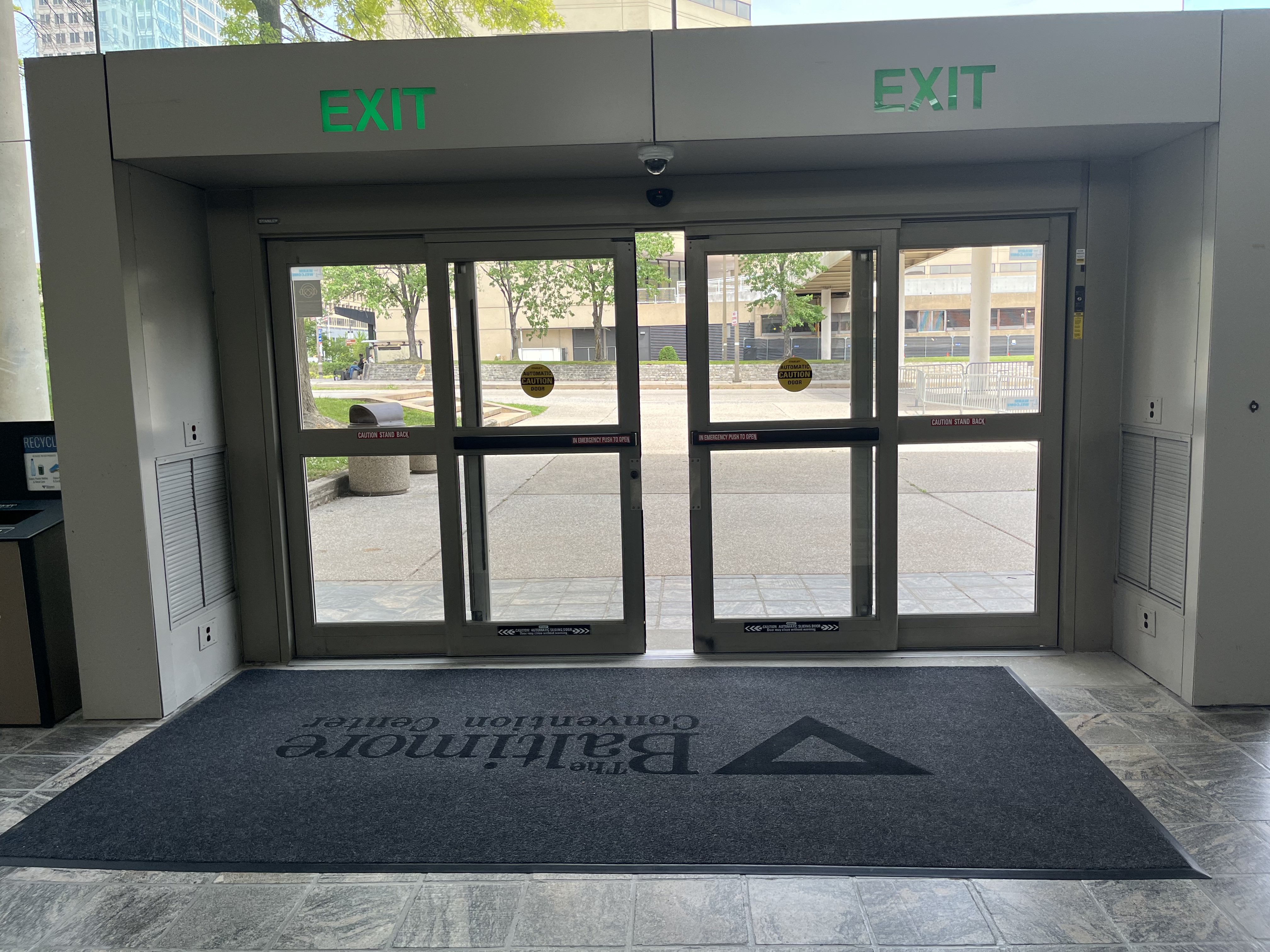 The photo shows a set of sliding glass doors taken from inside the Charles Street Lobby. Directly inside the doors is a gray floor mat.