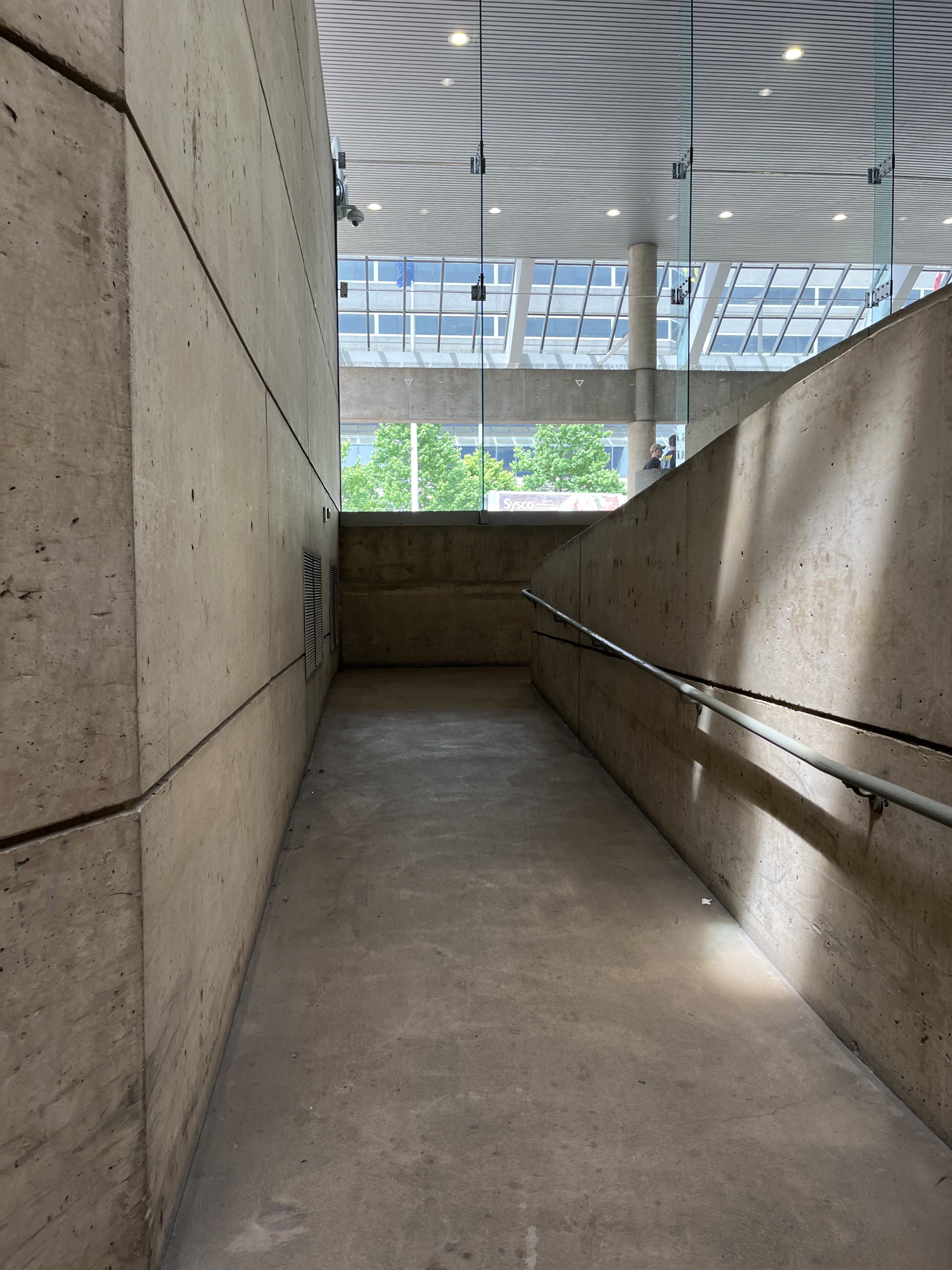 Photo showing a beige concrete ramp with a gray handrail on the left.