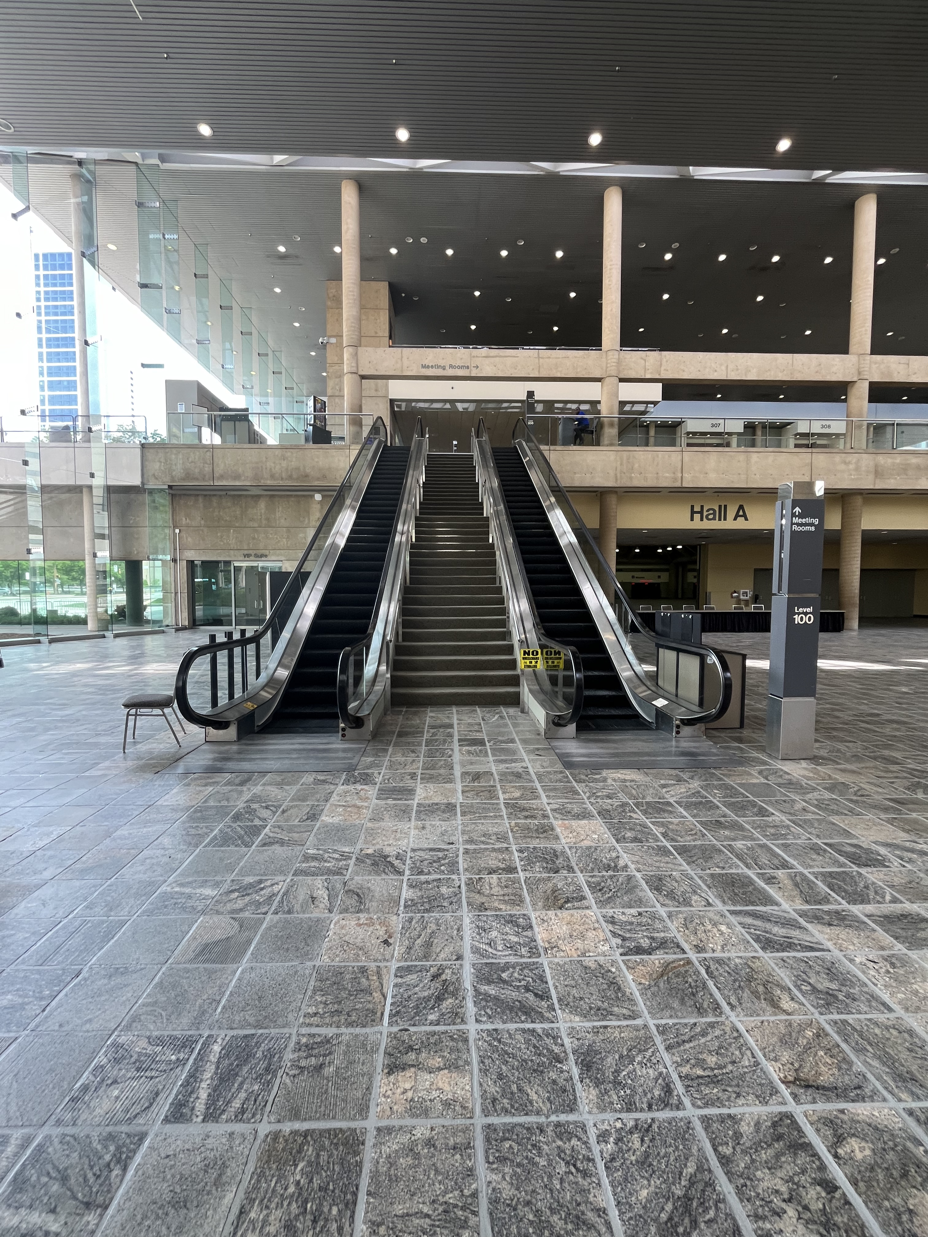 A photo at taken from Level 100 in the Charles Street Lobby of escalators on either side of a set of stairs.