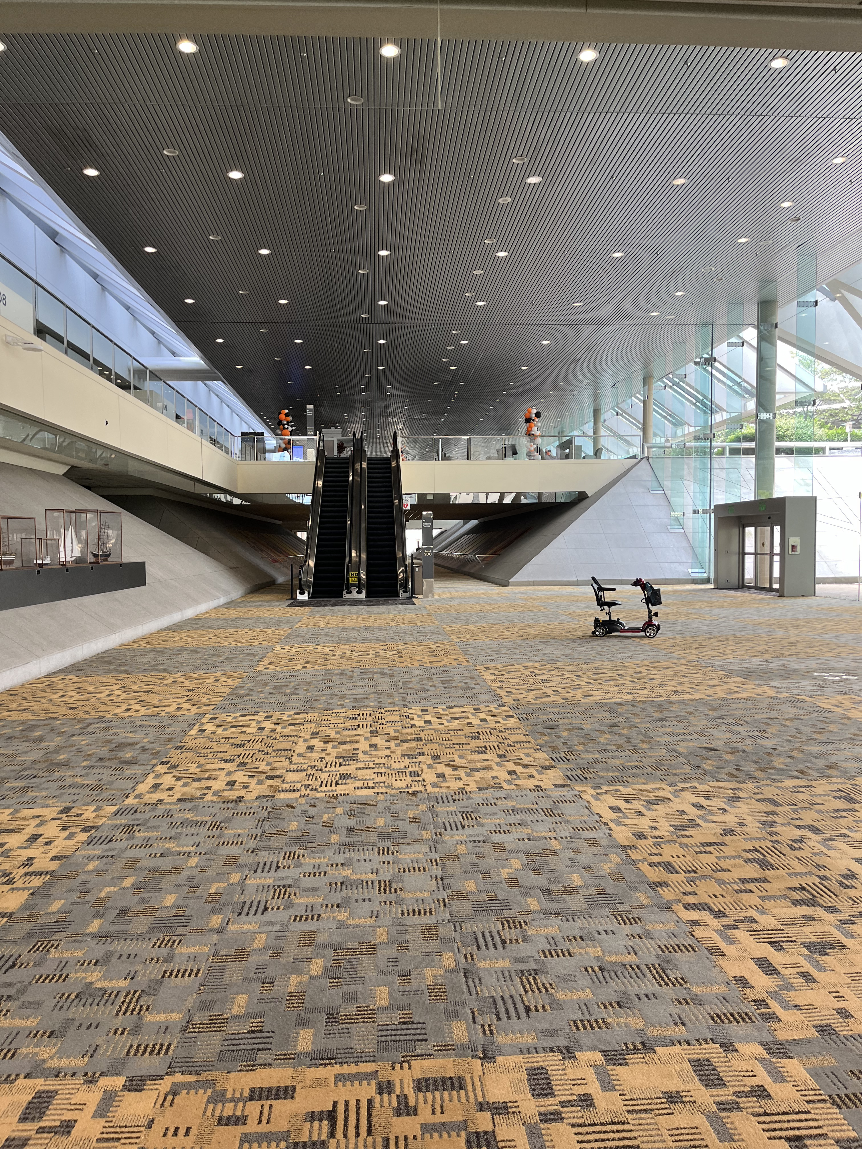 A wide hallway is pictured with a set of escalators at the end that lead to Level 300.