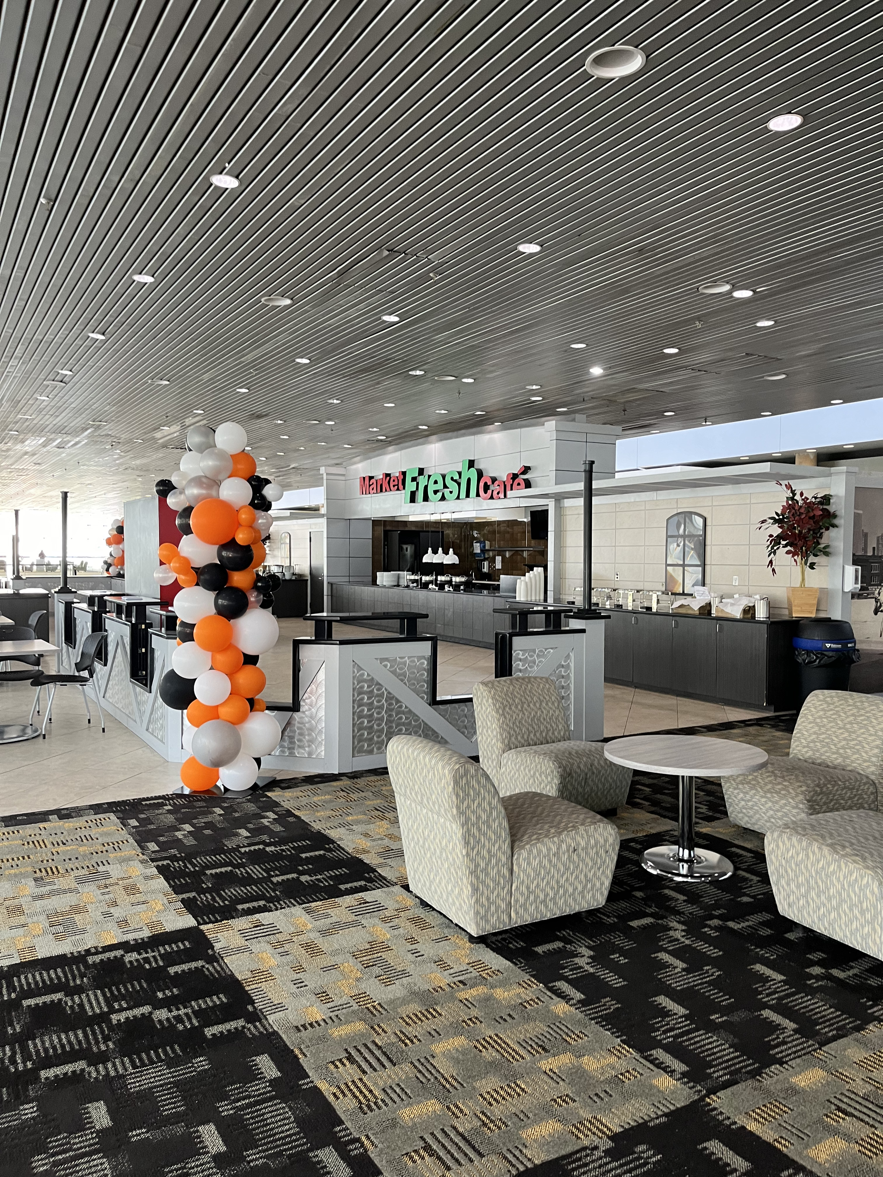 A photo of the lobby area at the top of the escalators on Level 300. There is a food and beverage stand called The Fresh Café, and mixed seating options surrounding it.
